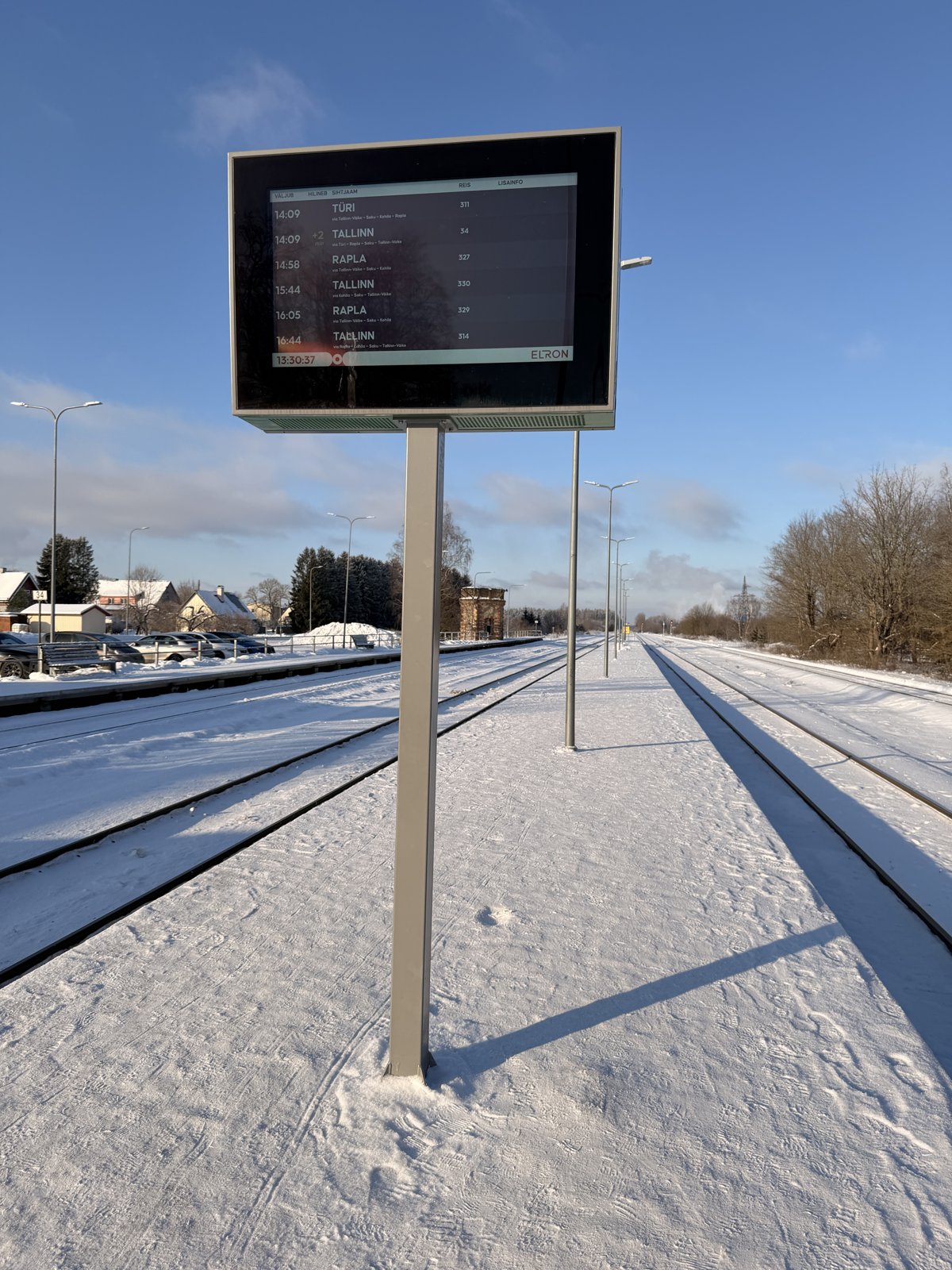 Ampron outdoor LCD passenger information display at a station on the Tallinn–Rapla line showing Elron departures to Türi, Rapla and Tallinn