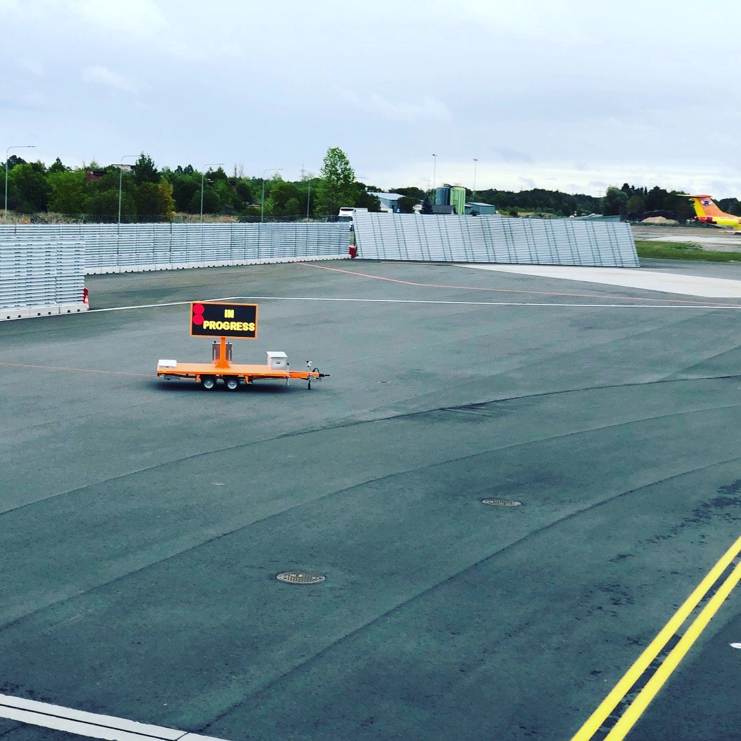 Ampron de-icing sign trailer on the open apron at Tallinn Airport, showing IN PROGRESS.