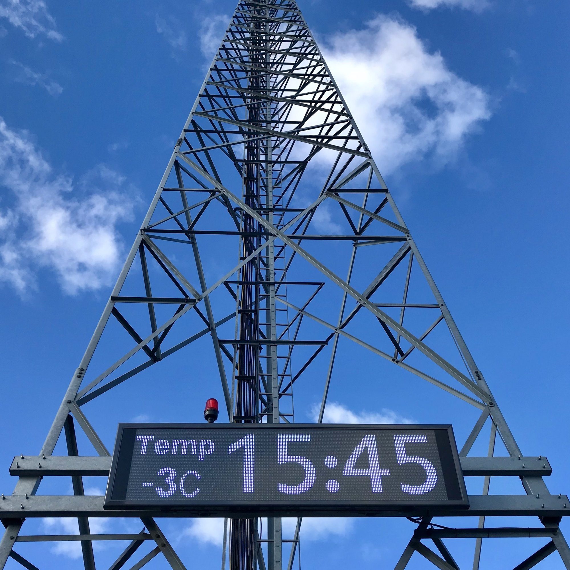 Ampron LED display on a lattice mast at Tallinn Airport showing NTP-synchronised time and temperature.